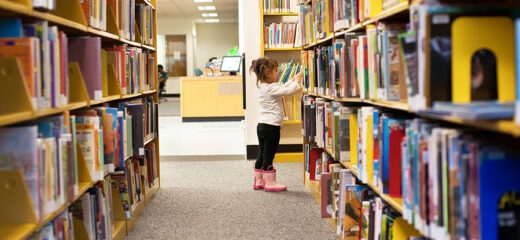 A young child browsing library bookshelves