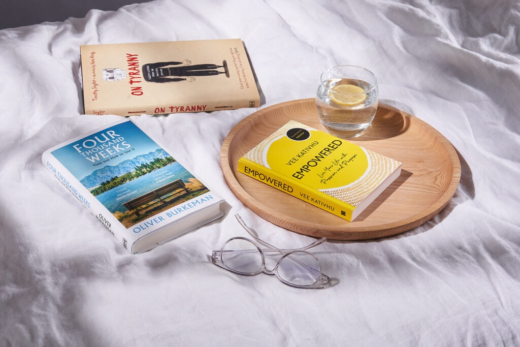 Three books - Empowered, Four Thousand Weeks and On Tyranny Graphic Edition - scattered on white bedsheets