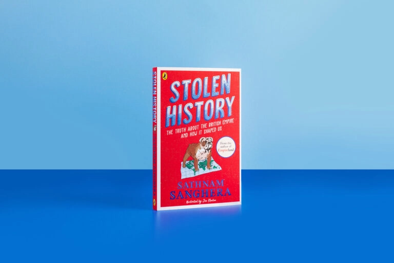 A photograph of the new book Stolen History by Sathnam Sanghera. The book cover is bright red with an illustration of an English bulldog standing on top of a map of the world. The book is in front of a light blue background and atop a darker blue surface.