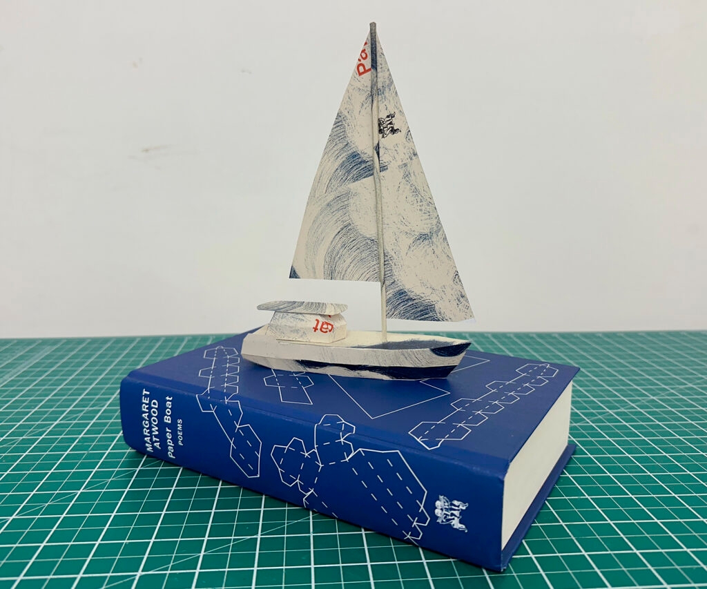 A paper boat on top of a copy of Paper Boat by Margaret Atwood