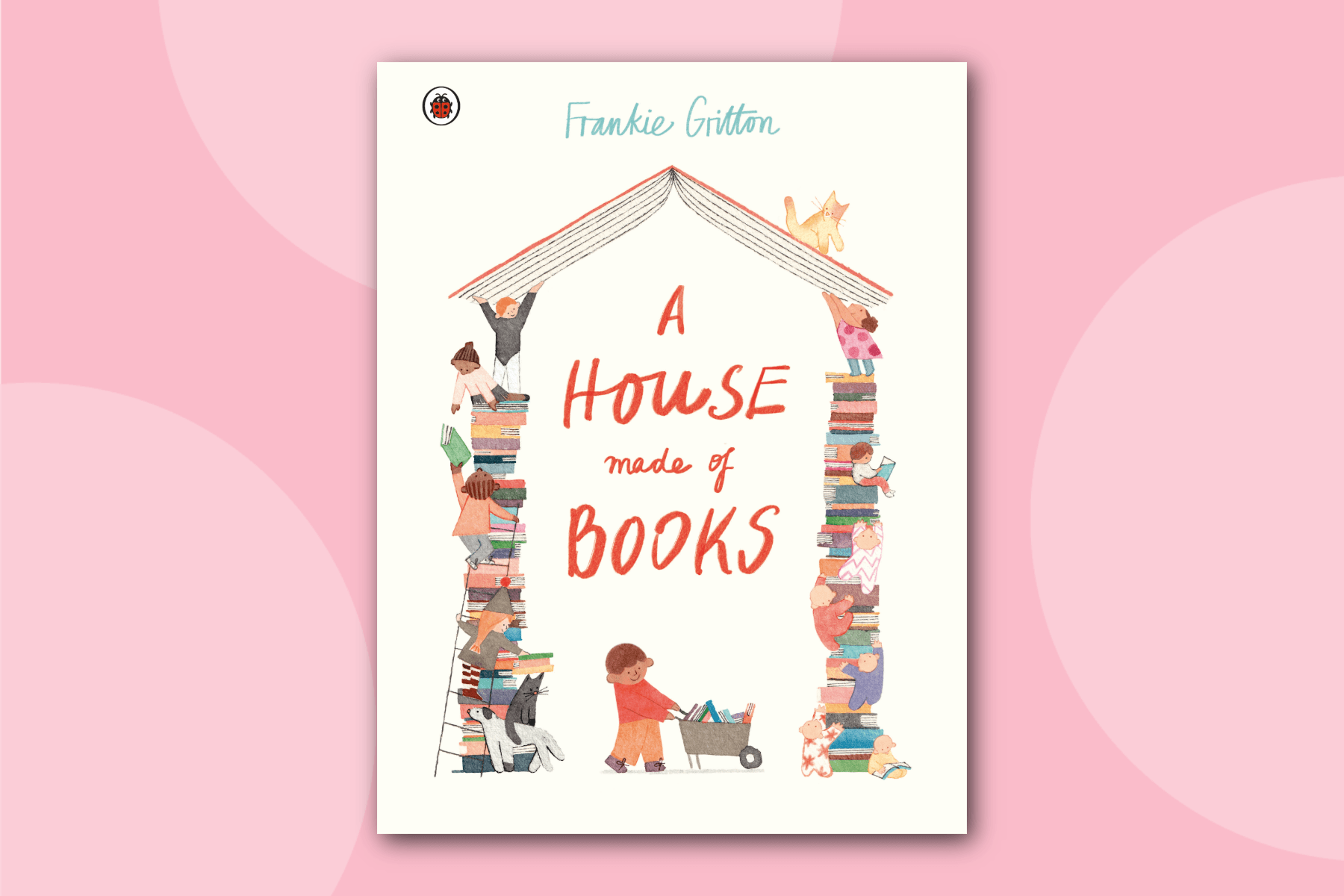 Book cover for 'A House Made of Books' by Frankie Gritton. The illustration shows a house made of an open book as the roof and two tall stacks of colorful books as walls. Children and animals are climbing, reading, and interacting with the books. A child pushes a wheelbarrow full of books at the bottom.