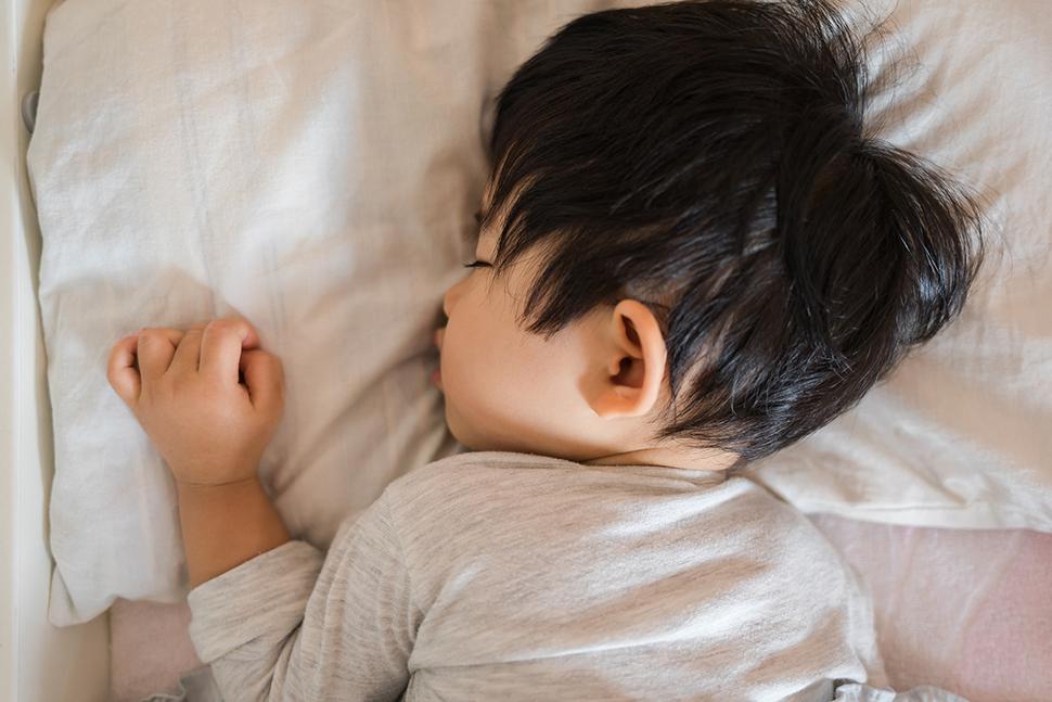 A photo of a little child laying down on the their front asleep
