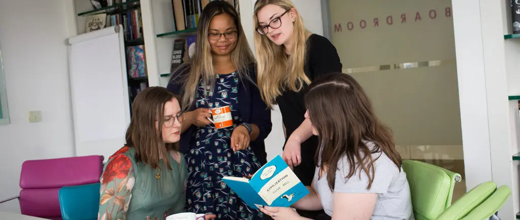 Colleagues talking and pointing at notebook in meeting