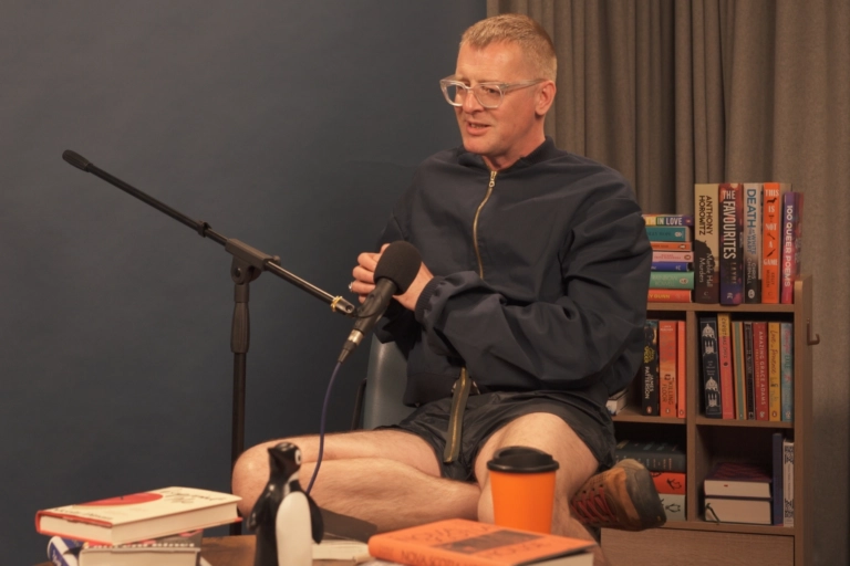 Nova Scotia House author Charlie Porter sitting and talking in the book-filled Penguin Podcast studio