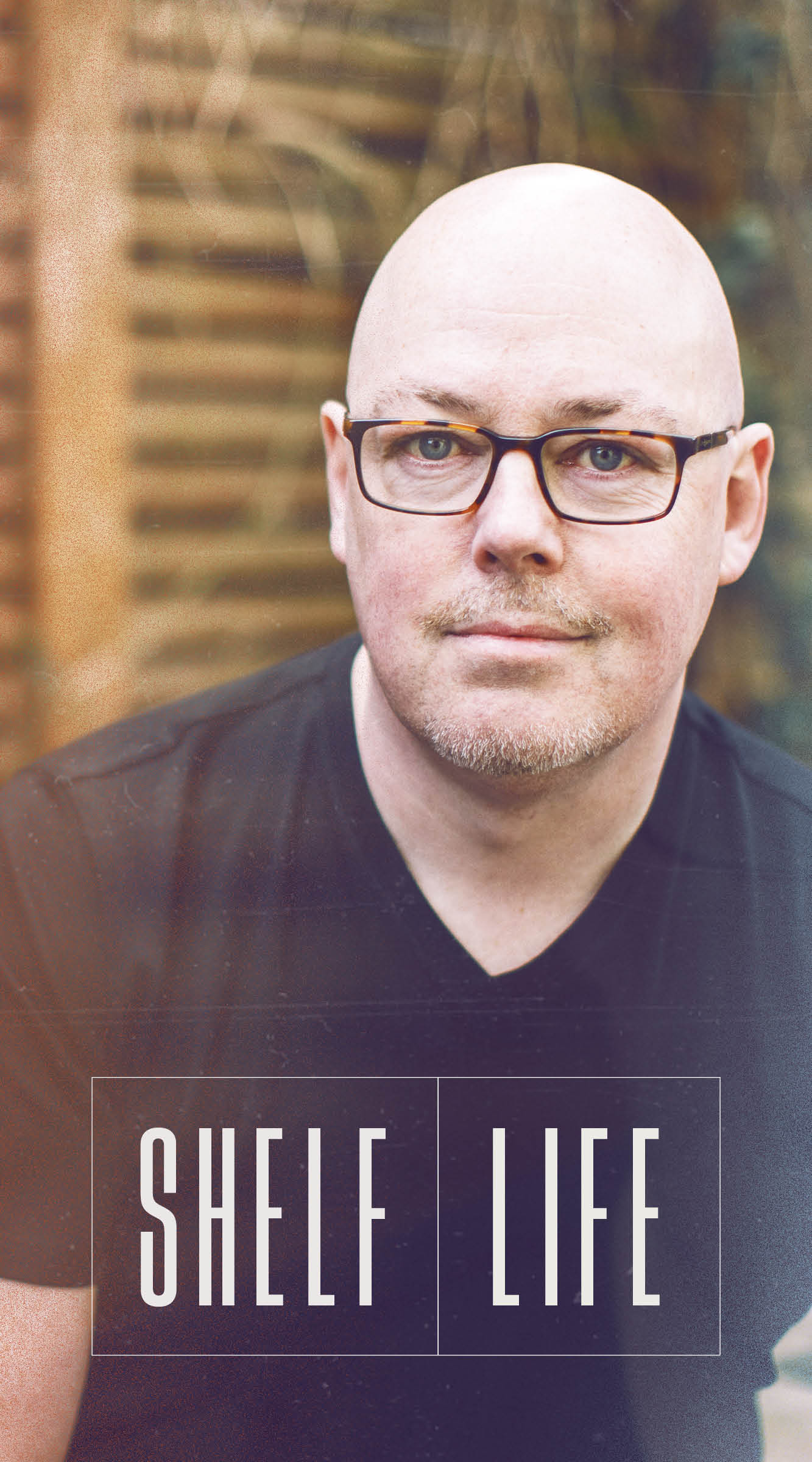 A photo of author John Boyne against a fence, with the words Shelf Life overlaid in white