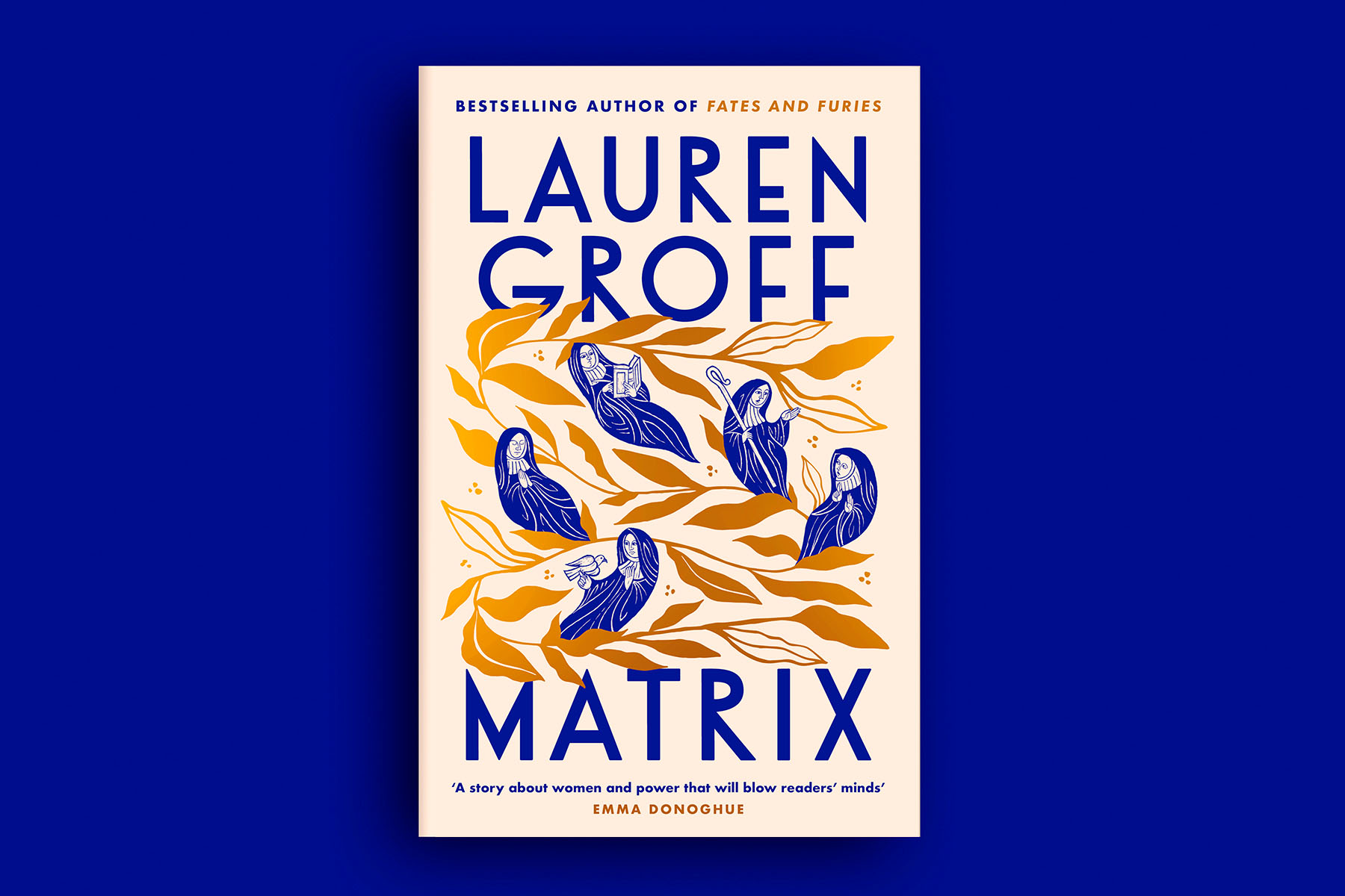 The cover of Matrix, by Lauren Groff, on a blue background. The cover is pale pink with gold leaf in the centre, and blue nuns float among the leaves.