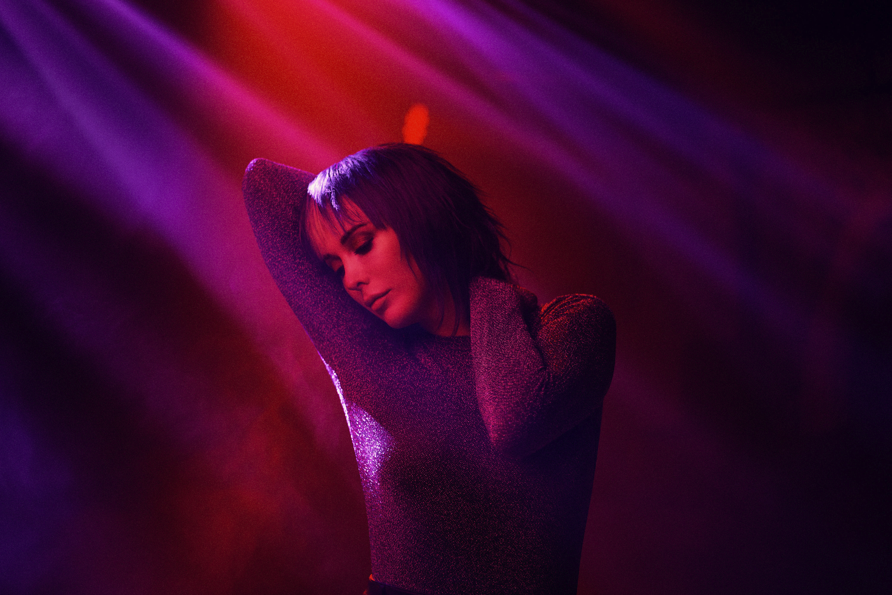 Paris Lees dancing in a black top against red and purple light