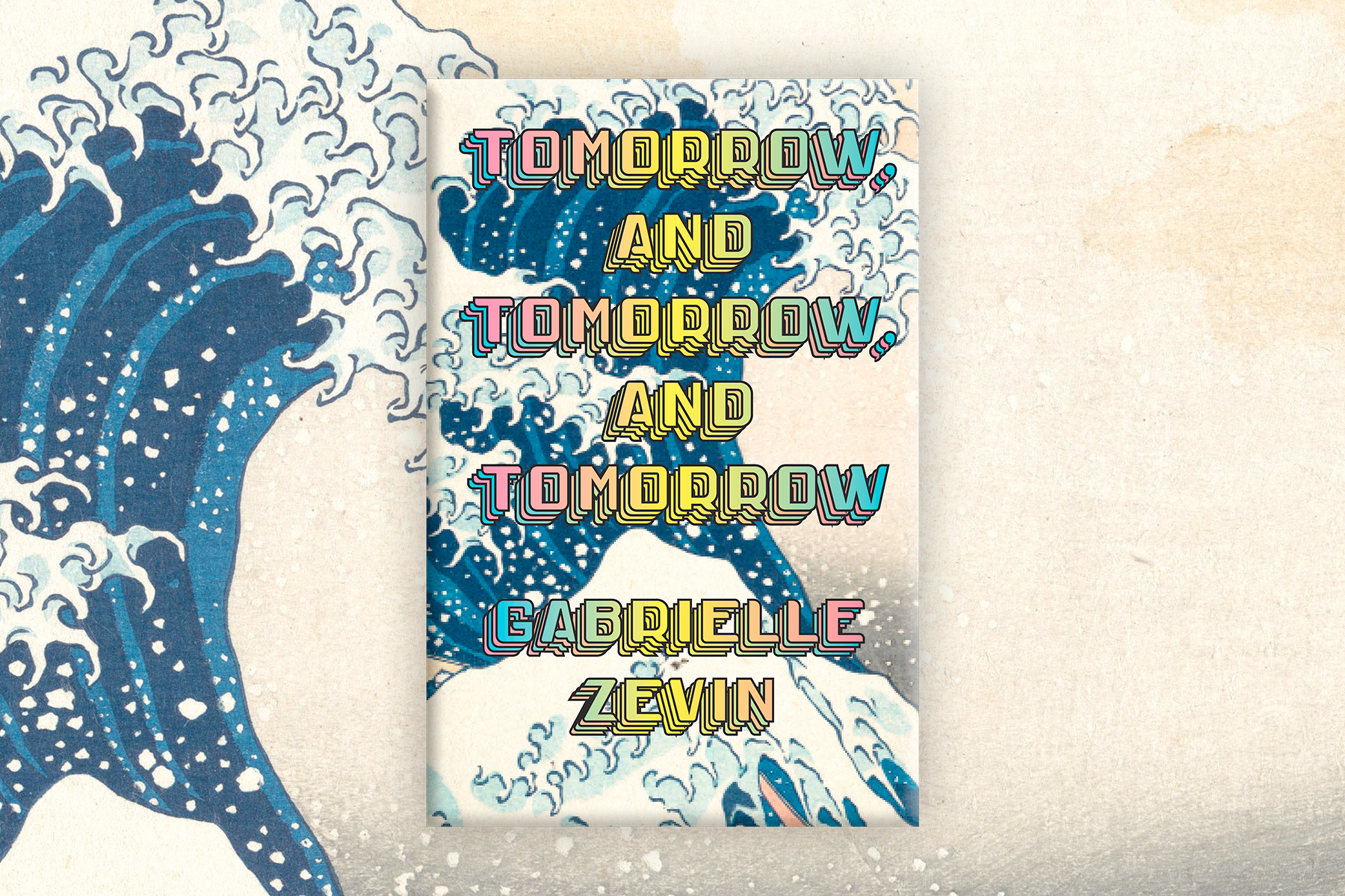 An image of the cover of Tomorrow, and Tomorrow, and Tomorrow by Gabrielle Zevin, with Hokusai's wave, which informs the design, as part of the background