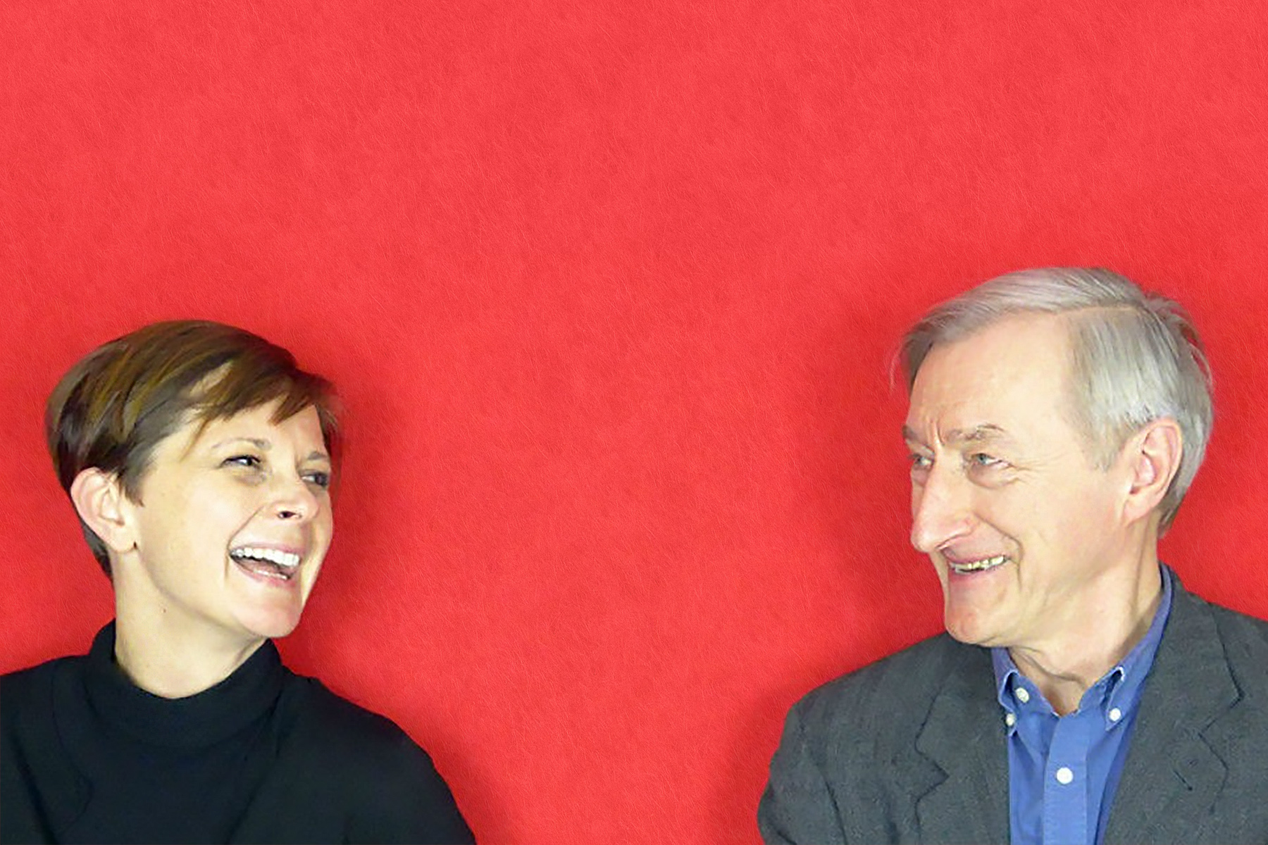 Photograph of Suzanne Dean and Julian Barnes from shoulders up, laughing to one another.