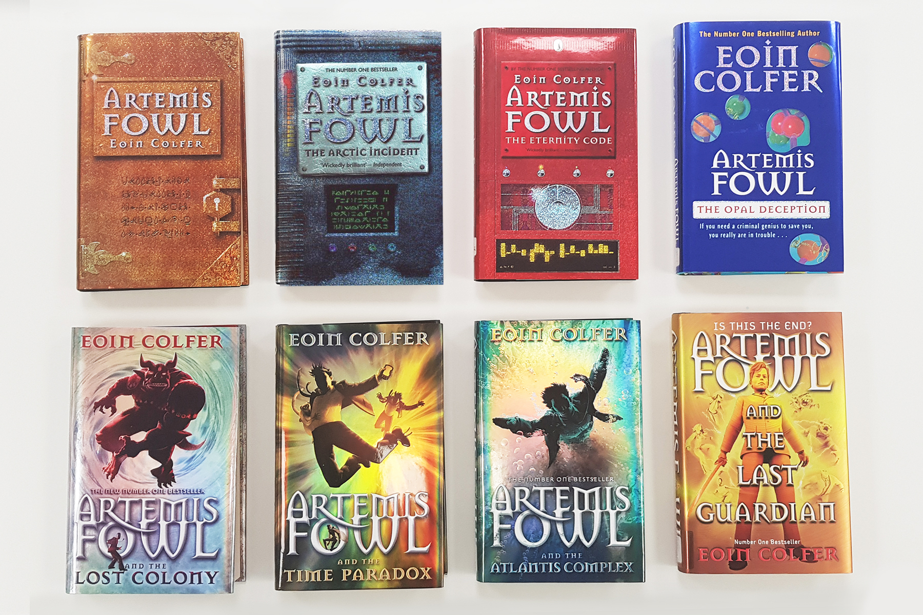 A photo of the original covers of the eight books in the Artemis Fowl series on a white background
