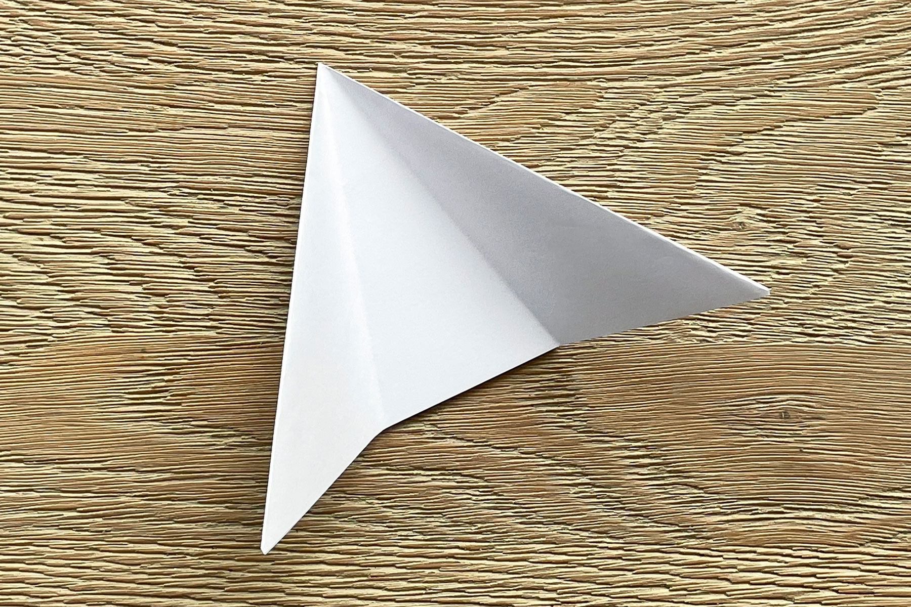 A photo of the diagonally folded square piece of paper being folded into thirds