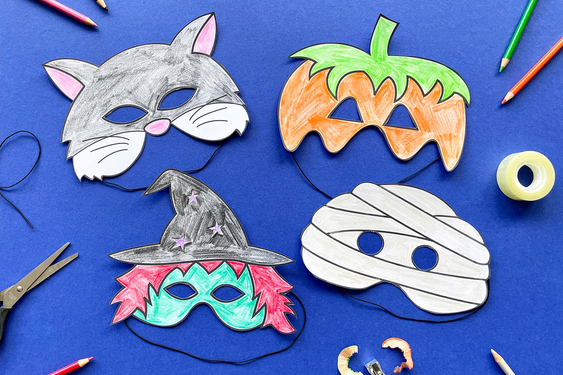 A photo of four cutout masks; a pumpkin, a witch, a cat and a mummy, coloured in and sitting on a dark blue background