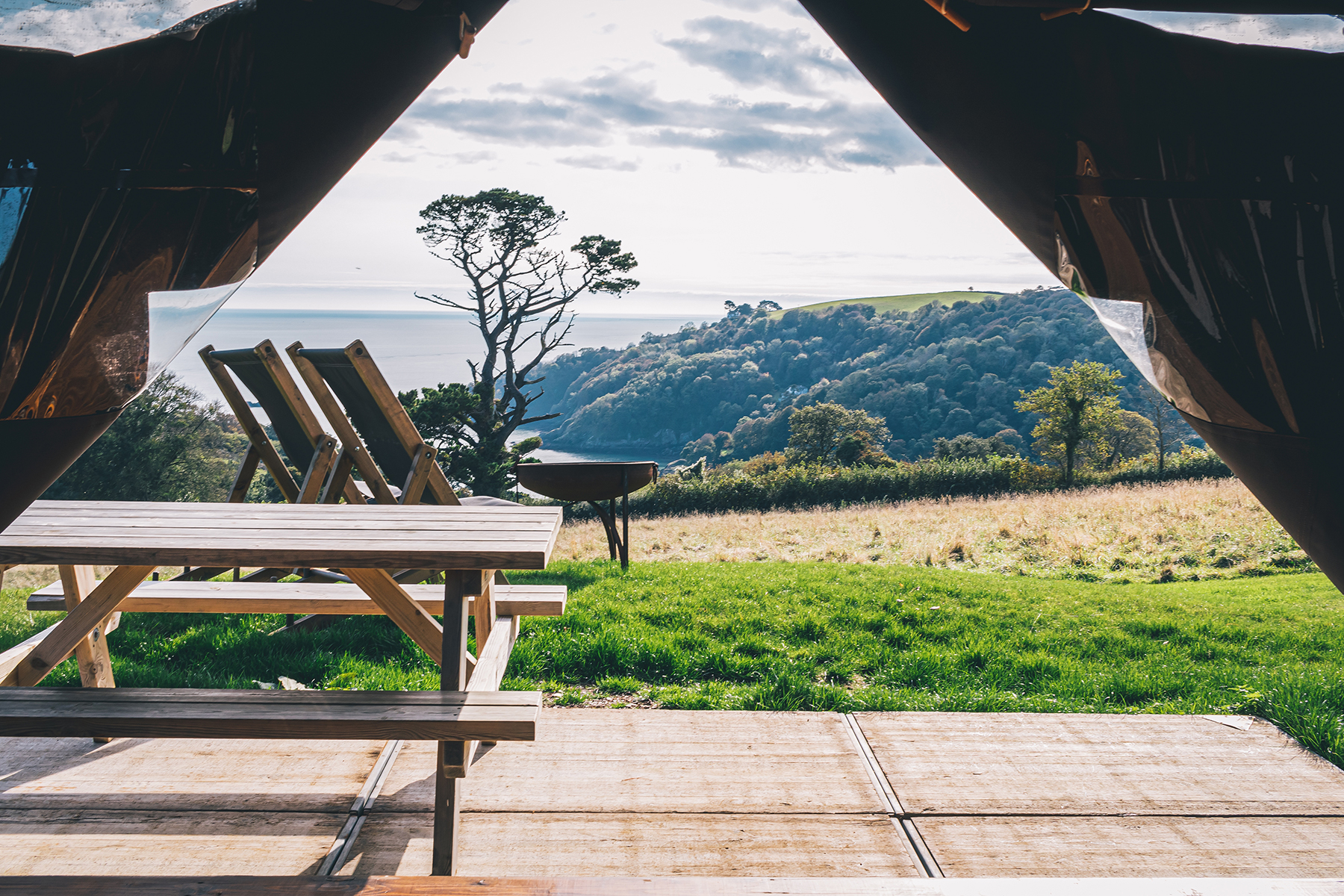 A photo from the inside of a tent showing a table and chairs with a beautiful farm background