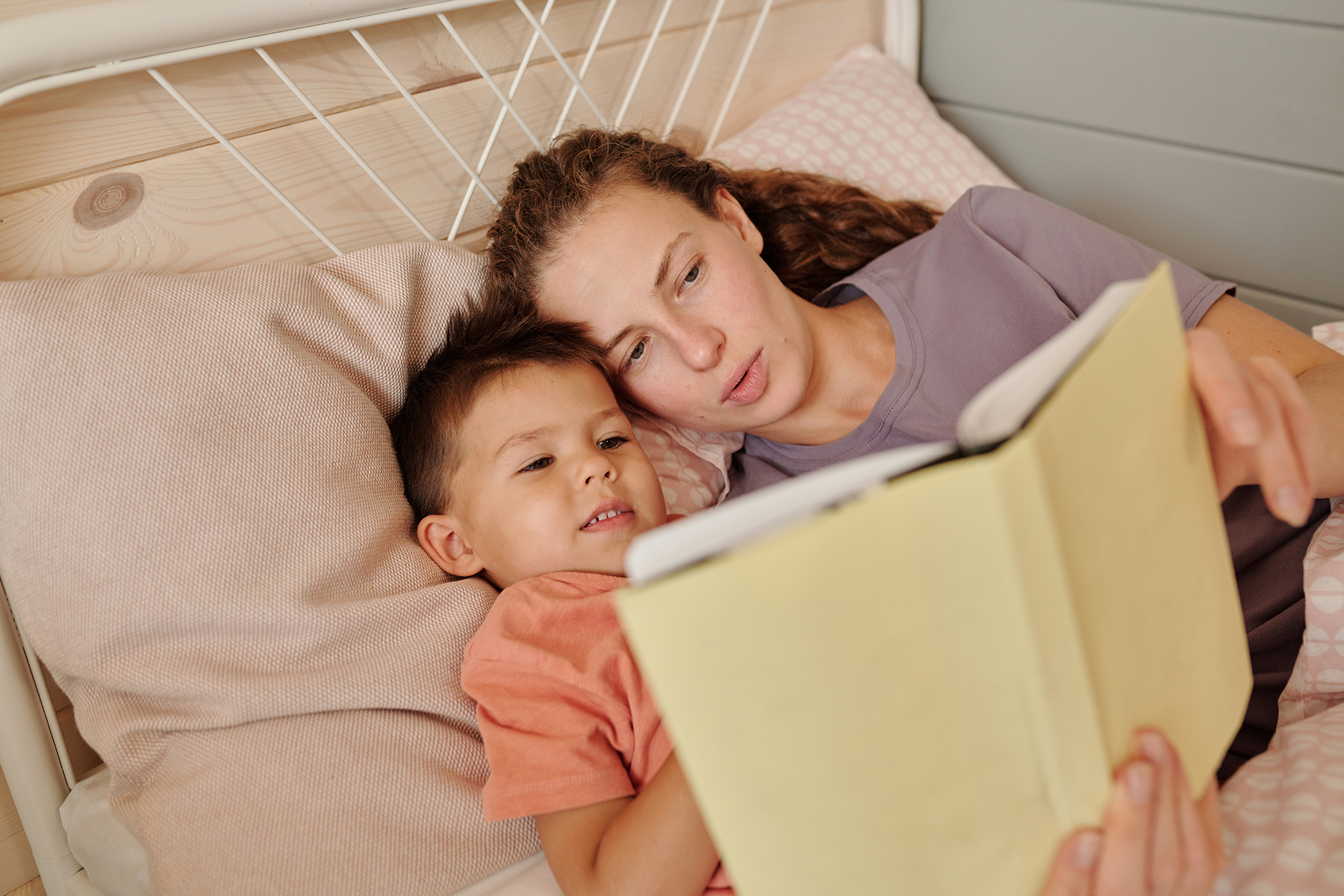 A photo of a mother and her son lying in bed and reading a bedtime story together