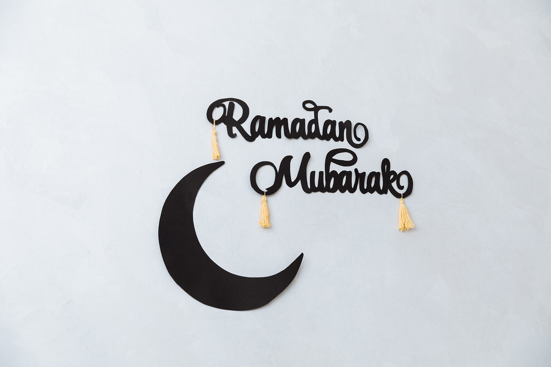 A photo of the words Ramadan Mubarak hung on a white wall with a crescent moon